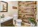 Stylish half bathroom featuring a wood accent wall, modern vanity, and decorative fixtures at 7703 S 68Th Dr, Laveen, AZ 85339