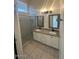 Bathroom featuring tiled floors, double vanity with granite countertop and framed mirrors, and a shower stall at 7728 W Via Montoya Dr, Peoria, AZ 85383