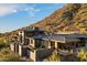 Stunning exterior view of a modern stone home nestled against a desert hillside with a metal roof and manicured landscaping at 9820 E Thompson Peak Pkwy # 629, Scottsdale, AZ 85255