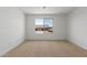 Bright bedroom featuring neutral walls, carpet floors, and a large window with neighborhood view at 11627 W Beck Ave, Youngtown, AZ 85363