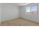 Bright, carpeted bedroom with a large window providing natural light and neighborhood views at 11627 W Beck Ave, Youngtown, AZ 85363
