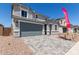 Two-story home showcasing a gray garage door, neutral stucco, decorative trim, and a paver driveway at 11627 W Beck Ave, Youngtown, AZ 85363