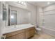 Bright bathroom featuring a large mirror, white countertop, wood cabinets, and a shower-tub combo at 13548 W Copperleaf Ln, Peoria, AZ 85383