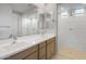 Bright bathroom featuring dual sinks, stylish mirrors, modern fixtures, and a separate glass-enclosed shower at 13548 W Copperleaf Ln, Peoria, AZ 85383