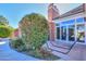 A covered backyard patio featuring a hammock, brick chimney, and a landscaped yard with lush greenery at 1520 E Elmwood Cir, Mesa, AZ 85203