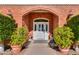 Close-up of a brick entryway that features an arched doorway, detailed door, and ornamental potted plants at 1520 E Elmwood Cir, Mesa, AZ 85203