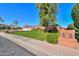Lovely single-story home with a manicured lawn, mature trees, and a charming brick facade at 1520 E Elmwood Cir, Mesa, AZ 85203