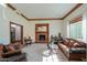 Cozy living room featuring a brick fireplace, carpet floors, a piano, and comfortable seating at 1520 E Elmwood Cir, Mesa, AZ 85203