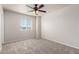 A bright carpeted bedroom featuring a ceiling fan and a sunlit window at 17254 W Marshall Ln, Surprise, AZ 85388