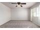 A bright carpeted bedroom featuring a ceiling fan and a sunlit window at 17254 W Marshall Ln, Surprise, AZ 85388