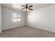 A carpeted bedroom with a ceiling fan and a window overlooking the neighborhood at 17254 W Marshall Ln, Surprise, AZ 85388