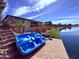 Scenic backyard with lake views, landscaping, steps to the water, and a blue paddle boat at 22360 N Daniel Dr, Maricopa, AZ 85138