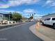 A sunny street view in a well-maintained manufactured home community with palm trees and paved roads at 2260 S Seminole Dr, Apache Junction, AZ 85119