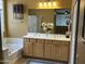 Bathroom boasts double sinks, wooden cabinets, and a soaking tub near a bright window at 22988 W Twilight Trl, Buckeye, AZ 85326