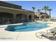 Community pool with many lounge chairs and palm trees at 22988 W Twilight Trl, Buckeye, AZ 85326