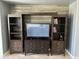 Entertainment center with a TV, storage and display shelves, and a wood paneled wall at 22988 W Twilight Trl, Buckeye, AZ 85326