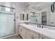 Bright bathroom featuring double sinks, a large mirror, and a glass-enclosed shower with decorative tile accents at 23764 N 162Nd Ave, Surprise, AZ 85387