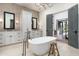 Bright bathroom features a standalone tub, dual sink vanity, a gray-brick accent wall, and a view to the backyard at 27914 N 100Th Pl, Scottsdale, AZ 85262