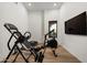 Bright exercise room with wood floors, black framed window, inversion table, rowing machine, and wall-mounted TV at 27914 N 100Th Pl, Scottsdale, AZ 85262