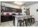 Well-lit kitchen with dark cabinetry, a granite island with seating and stainless steel appliances at 2922 W Kowalsky Ln, Phoenix, AZ 85041