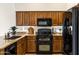 Well-lit kitchen with granite counters, wood cabinets, black appliances, and tile flooring at 3431 S Felix Way, Chandler, AZ 85248