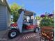 A well-maintained golf cart parked on a brick patio with vibrant flowers and landscaping at 650 N Hawes Rd # 4716, Mesa, AZ 85207