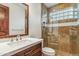 Bathroom featuring walk-in shower with travertine surround and custom wood vanity at 7111 E Sienna Bouquet Pl, Scottsdale, AZ 85266