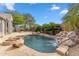 Backyard pool featuring a rock waterfall, fire pit, desert plants and a stone patio at 7111 E Sienna Bouquet Pl, Scottsdale, AZ 85266
