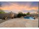 Serene pool area featuring a waterfall, lush greenery, and a stone patio under a colorful sky at 7111 E Sienna Bouquet Pl, Scottsdale, AZ 85266