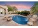 Stunning backyard pool with a rock waterfall feature, a fire pit, and lush desert landscaping at 7111 E Sienna Bouquet Pl, Scottsdale, AZ 85266