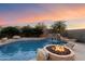 Stunning pool with a waterfall and a cozy fire pit area, set against a backdrop of a vibrant sunset at 7111 E Sienna Bouquet Pl, Scottsdale, AZ 85266