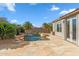 Beautiful backyard with a pool, rock waterfall, desert landscaping, and stone patio at 7111 E Sienna Bouquet Pl, Scottsdale, AZ 85266
