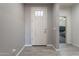 A bright entryway with wood-look tile flooring and a white front door is next to a view of the bedroom at 7552 W Darrel Rd, Laveen, AZ 85339