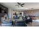 Open-concept living room featuring dark sofas, ceiling fan, stylish wood-look flooring, and kitchen access at 7552 W Darrel Rd, Laveen, AZ 85339