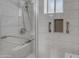 This shower features a glass door, decorative tiles, and convenient grab bars at 8064 E Madero Ave, Mesa, AZ 85209