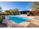 Backyard pool area with a covered patio, lush landscaping and mature trees in the background at 8155 E Juan Tabo Rd, Scottsdale, AZ 85255