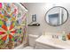 Bright bathroom with colorful shower curtain, round mirror, and vanity with sink at 8551 E Kiowa Ave, Mesa, AZ 85209