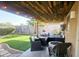 An outdoor patio with wood covering, a fire table, turf, a lounging sofa and a grill at 8662 W Paradise Ln, Peoria, AZ 85382