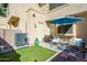 View of the back patio, including an AC unit, artificial turf, and outdoor seating with an umbrella at 921 W University Dr # 1143, Mesa, AZ 85201