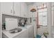 Clean laundry room with appliances, white cabinets, and a charming, decorated window at 10801 W Mountain View Rd, Sun City, AZ 85351