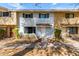 Two-story townhome with light brick and dark shutters, accented by mature landscaping and a paved walkway at 1575 W Hazelwood St, Phoenix, AZ 85015
