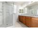 Bathroom featuring double sinks, granite countertops, wood cabinets, a glass shower, and bright lighting at 2090 S Dorsey Ln # 1020, Tempe, AZ 85282
