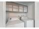 Well-lit laundry room equipped with washer, dryer, and overhead cabinets for storage at 2440 N 22Nd Ave, Phoenix, AZ 85009