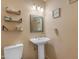 Charming bathroom featuring a pedestal sink, mirror, floating shelves and three-light vanity fixture at 2966 S Country Club Way, Tempe, AZ 85282