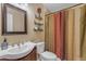 Bathroom featuring a cherry vanity with a white sink, decorative mirror, and a shower with a colorful curtain at 2966 S Country Club Way, Tempe, AZ 85282