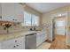 Bright kitchen with white cabinets, stainless steel dishwasher, and rustic terracotta tile flooring at 2966 S Country Club Way, Tempe, AZ 85282