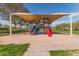 Community playground features covered play structure surrounded by lush green space under clear blue sky at 3062 E Cullumber St, Gilbert, AZ 85234