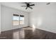 A spacious bedroom boasts wood-look laminate flooring, a ceiling fan, and two sunny windows with views at 4111 N 313Th Ave, Buckeye, AZ 85396