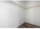 This walk-in closet features a wooden clothes rack, white walls, and dark brown wood-look laminate flooring at 4111 N 313Th Ave, Buckeye, AZ 85396