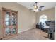 Home office showcasing a dark wood display cabinet, ceiling fan, and arched window with a home office setup at 4365 S Columbine Way, Gold Canyon, AZ 85118